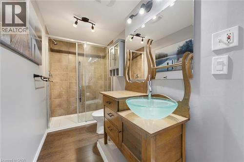 Wood-finish flooring, glass vessel sink, track lighting, tiled shower with glass enclosure, custom vanity - 592 Little Dover Crescent, Waterloo, ON - Indoor Photo Showing Bathroom