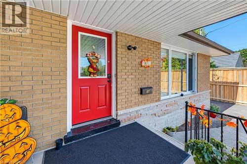 Brick exterior with a vibrant red entry door featuring a full-light insert - 87 Bond Street, Kitchener, ON 