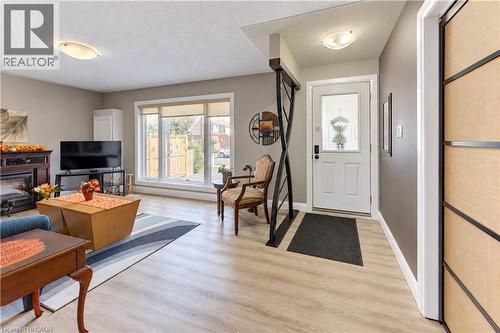 Light wood-finish flooring throughout, a large picture window, a built-in fireplace, and a decorative interior railing - 87 Bond Street, Kitchener, ON 