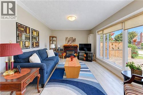Light wood-finish flooring, a decorative fireplace, large windows with roller shades, and crown molding - 87 Bond Street, Kitchener, ON 