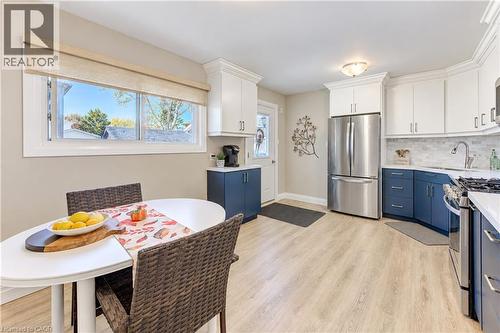 Kitchen featuring two-tone cabinetry, stainless steel appliances, light wood-finish flooring, and a window with a roller shade - 87 Bond Street, Kitchener, ON 