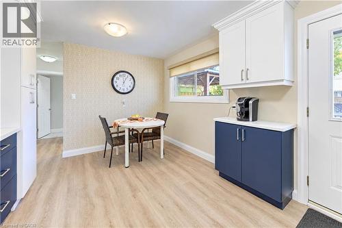 Wood-finish flooring, white built-in cabinetry with crown molding, a built-in lower cabinet with a light-colored countertop, and a window with a roller shade - 87 Bond Street, Kitchener, ON 