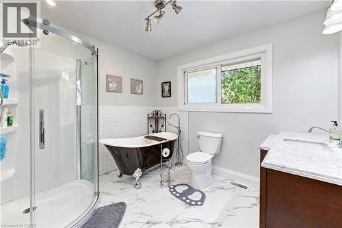 Curved glass shower enclosure, freestanding clawfoot tub, single vanity with light-toned countertop, and a sliding window - 87 Bond Street, Kitchener, ON 