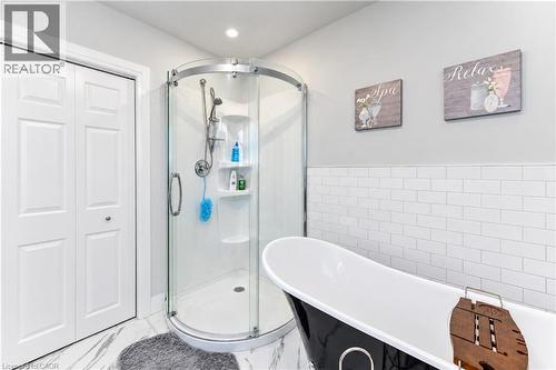 White subway tile wainscoting and a freestanding black and white bathtub - 87 Bond Street, Kitchener, ON 