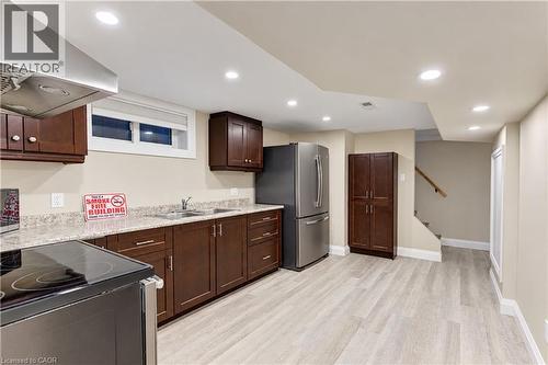 Kitchenette featuring dark wood cabinetry, light wood-finish flooring, recessed lighting, stainless steel appliances, and a double basin sink - 87 Bond Street, Kitchener, ON 