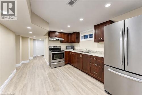 Kitchen area featuring stainless steel appliances, dark wood cabinetry, and light-toned countertops - 87 Bond Street, Kitchener, ON 