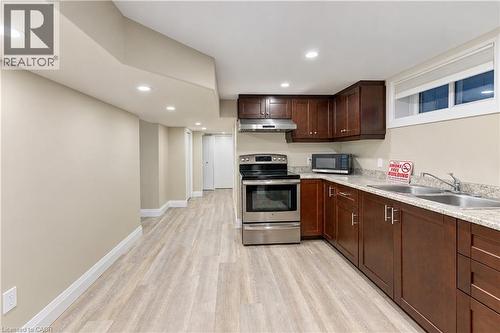 Kitchenette featuring wood-finish flooring, recessed lighting, wood cabinetry, stainless steel appliances, and light-toned countertops - 87 Bond Street, Kitchener, ON 