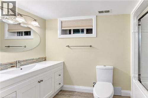 White vanity with brushed nickel hardware, undermount sink, mosaic tile backsplash, and a contemporary wall-mounted light fixture - 87 Bond Street, Kitchener, ON 