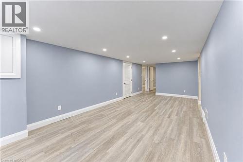 Spacious room with wood-finish flooring, recessed lighting, light blue wall paint, and white trim - 87 Bond Street, Kitchener, ON 