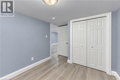 Light blue painted walls, wood-finish flooring, white trim, and white bi-fold closet doors - 87 Bond Street, Kitchener, ON 