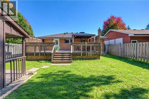 Expansive backyard featuring a green lawn, multi-level wooden deck, wooden privacy fencing, and a built-in gazebo structure - 87 Bond Street, Kitchener, ON 