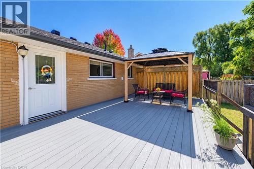 Expansive grey composite decking with a built-in gazebo featuring a dark metal roof, brick exterior, and white entry door with decorative glass - 87 Bond Street, Kitchener, ON 