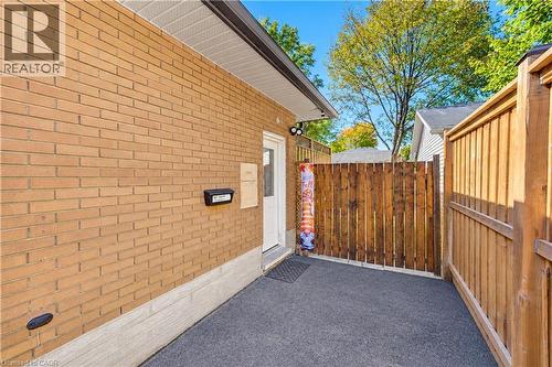Brick exterior, wood privacy fencing, side entry door, black exterior mailbox, textured ground surface - 87 Bond Street, Kitchener, ON 