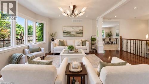 Open concept living area featuring expansive windows, wood-finish flooring, and a decorative ceiling light fixture - 56 Windrush Trail, Kitchener, ON 
