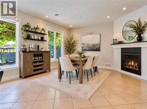 Recessed lighting illuminates the dining area with a built-in fireplace, tile flooring, and large windows - 56 Windrush Trail, Kitchener, ON 