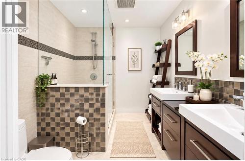 Dual vanity with vessel sinks, glass-enclosed shower, tiled half-wall, recessed lighting, and wall-mounted vanity lighting - 56 Windrush Trail, Kitchener, ON 
