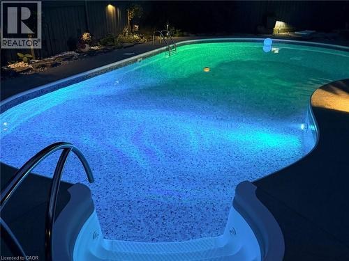 Swimming pool with integrated lighting, metal handrails, and a textured pool floor - 56 Windrush Trail, Kitchener, ON 