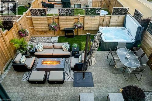 Private backyard featuring a hot tub, stone-finish patio, fenced perimeter, and a fire pit - 65 Waterview Lane, Grimsby, ON 
