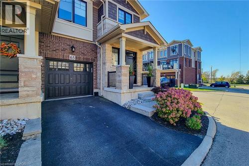 Brick and stone façade with dark trim, featuring a covered front entry and a dark paneled garage door - 65 Waterview Lane, Grimsby, ON 