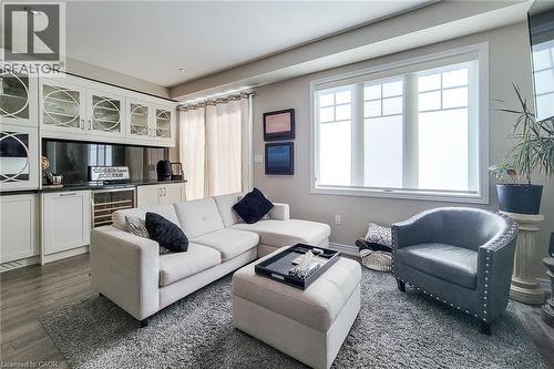 Built-in bar with glass-front cabinetry, under-counter wine refrigerator, and dark countertops - 65 Waterview Lane, Grimsby, ON 