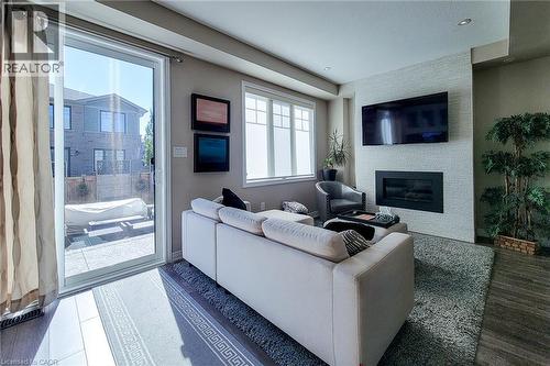 Sliding glass patio doors, built-in electric fireplace, textured accent wall, recessed lighting, and wood-finish flooring - 65 Waterview Lane, Grimsby, ON 