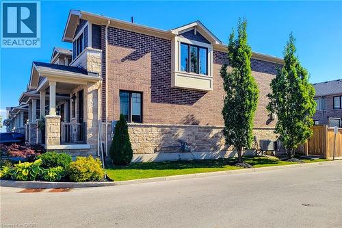 Brick and stone exterior with a covered porch, bay window, and manicured landscaping - 65 Waterview Lane, Grimsby, ON 