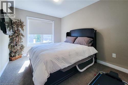 Wall-mounted television fixture, window with roller shade, neutral wall paint, and gray carpet flooring - 65 Waterview Lane, Grimsby, ON 