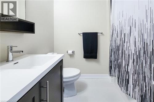 Vanity with a white integrated sink, chrome faucet, and dark wood cabinetry - 65 Waterview Lane, Grimsby, ON 