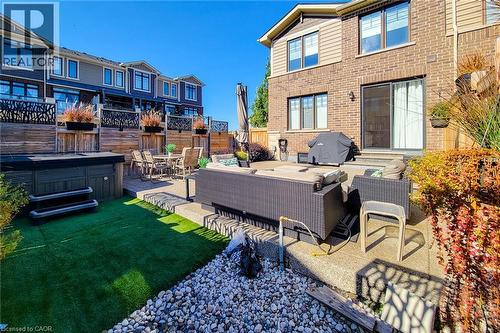 Expansive backyard featuring a hot tub, artificial turf, and a multi-level patio with decorative privacy screens - 65 Waterview Lane, Grimsby, ON 