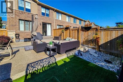 Expansive outdoor patio with concrete paving, wood fencing, and a combination of faux turf and decorative stone landscaping - 65 Waterview Lane, Grimsby, ON 