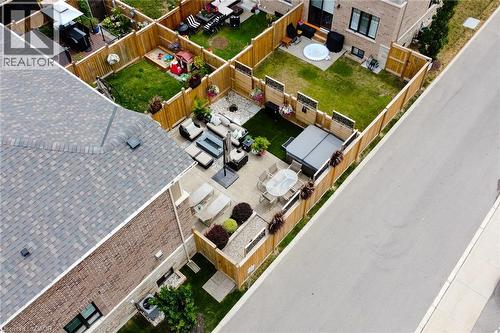 Expansive paved patio area featuring a hot tub, artificial turf, and wood privacy fencing - 65 Waterview Lane, Grimsby, ON 