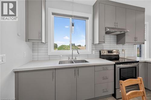Gray cabinetry with modern hardware, light-toned countertops, subway tile backsplash, stainless steel range, and stainless steel range hood - 41 Eleanor Avenue, Hamilton, ON 