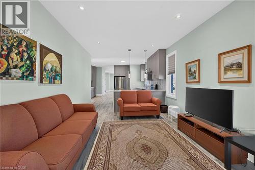 Open-concept living area featuring recessed lighting, wood-finish flooring, and a kitchen with gray cabinetry and stainless steel appliances - 41 Eleanor Avenue, Hamilton, ON 