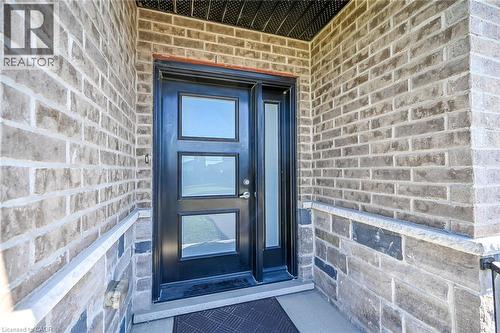 Entryway featuring a black door with three glass inserts, a coordinating sidelight, and a brick exterior with stone detailing - 41 Eleanor Avenue, Hamilton, ON 