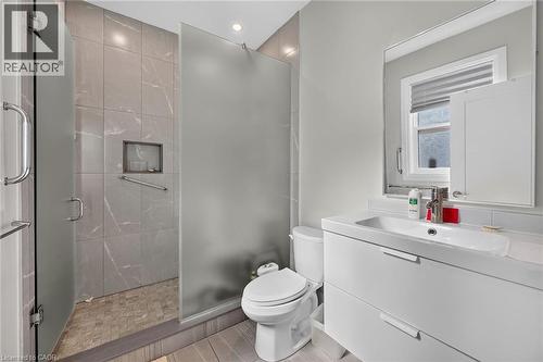 Modern bathroom featuring a walk-in shower with a frosted glass enclosure and gray tiled walls - 41 Eleanor Avenue, Hamilton, ON 