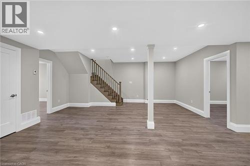 Spacious finished room with wood-finish flooring, recessed lighting, and a prominent staircase with wood railings - 41 Eleanor Avenue, Hamilton, ON 