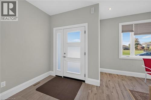 Entryway featuring a white door with frosted glass panels, a full-length sidelight, and wood-finish flooring - 41 Eleanor Avenue, Hamilton, ON 
