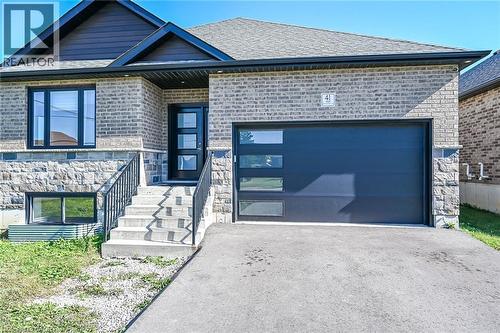 Brick and stone facade with dark framed windows, a contemporary entry door, and an attached single-car garage - 41 Eleanor Avenue, Hamilton, ON 