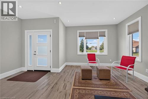 Recessed lighting, wood-finish flooring, white trim, modern entry door with frosted glass panels, and multiple windows - 41 Eleanor Avenue, Hamilton, ON 