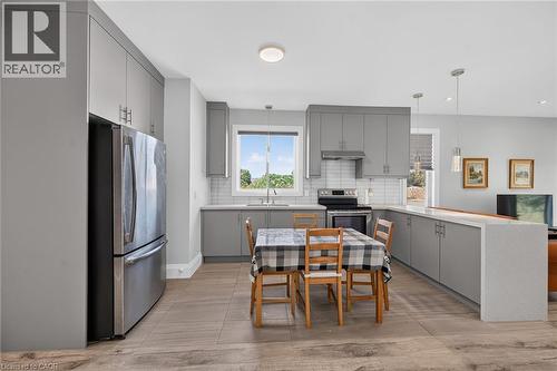 Kitchen featuring light gray cabinetry, stainless steel appliances, white subway tile backsplash, and light-toned countertops - 41 Eleanor Avenue, Hamilton, ON 