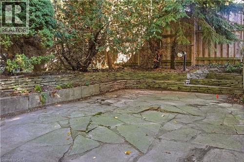 Stone patio with a tiered retaining wall, integrated planter, and mature perimeter trees - 12 Hill Street, Kitchener, ON 