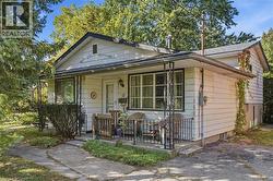 Front facade with a covered porch, white siding, and a gabled roofline - 
