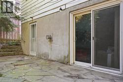 Stonework patio with a sliding glass door entry and an additional side entry door - 