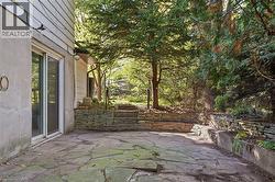Stone patio with irregular flagstone paving, multiple stacked stone retaining walls, and mature trees - 