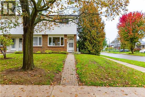 Exterior featuring a brick and horizontal siding façade, a paved walkway, and mature landscaping - 227 Fergus Avenue, Kitchener, ON 