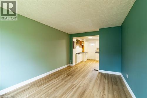 Interior space featuring wood-finish flooring, two-toned wall color, and kitchen area with white cabinetry and dark countertops - 227 Fergus Avenue, Kitchener, ON 