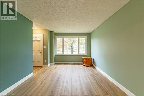 Room featuring wood-finish flooring, a large picture window, and a single-light panel front door - 227 Fergus Avenue, Kitchener, ON 