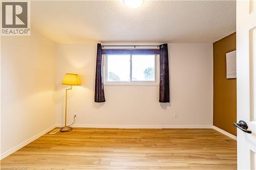 Interior space featuring wood-finish flooring, a neutral color palette with an accent wall, and a horizontal sliding window - 227 Fergus Avenue, Kitchener, ON 