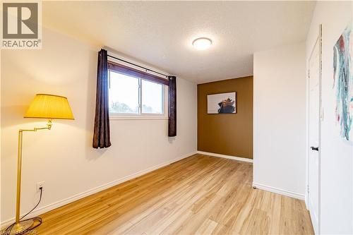 Wood-finish flooring, accent wall, and sliding window with overhead flush-mount lighting - 227 Fergus Avenue, Kitchener, ON 