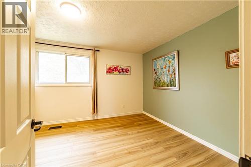 Wood-finish flooring, light-filled interior, and an accent wall featuring a soft green finish - 227 Fergus Avenue, Kitchener, ON 